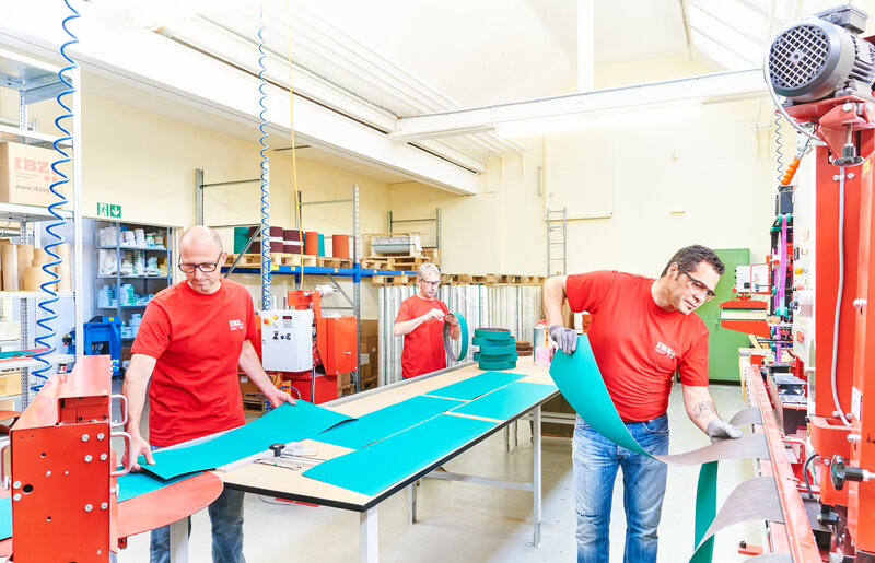 L'illustration montre le traitement/la transformation d'abrasifs dans la production IBZ. L'abrasif est adapté aux besoins du client. Sur la photo, on voit deux hommes,